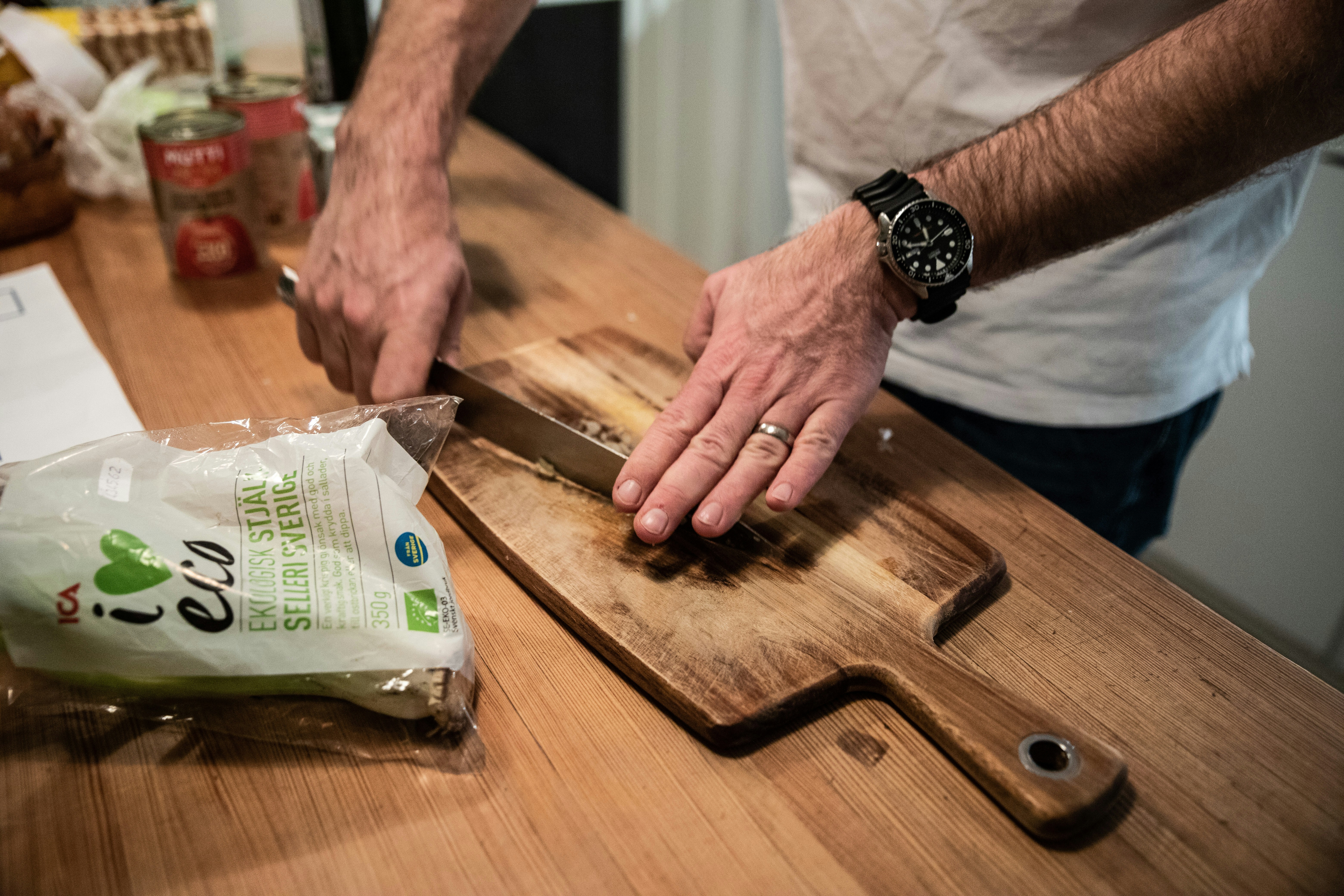 검은색 가죽 스트랩 시계를 차고 갈색 나무 도마를 들고 있는 사람