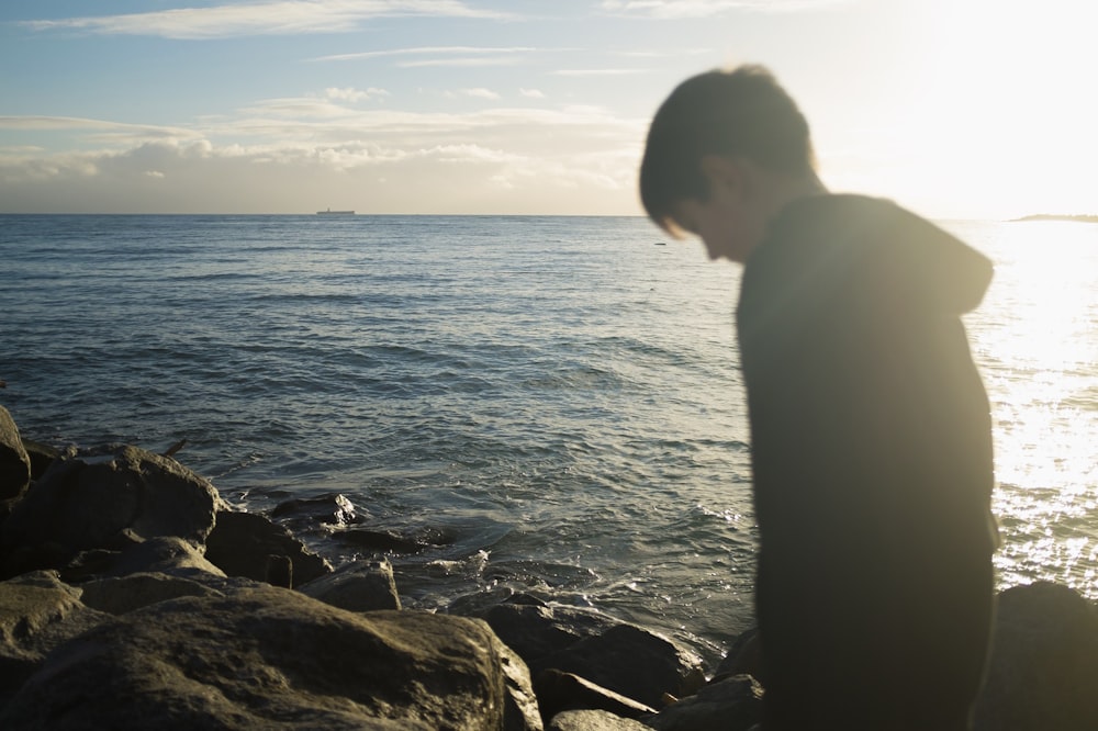 man standing on black rock formation during daytime