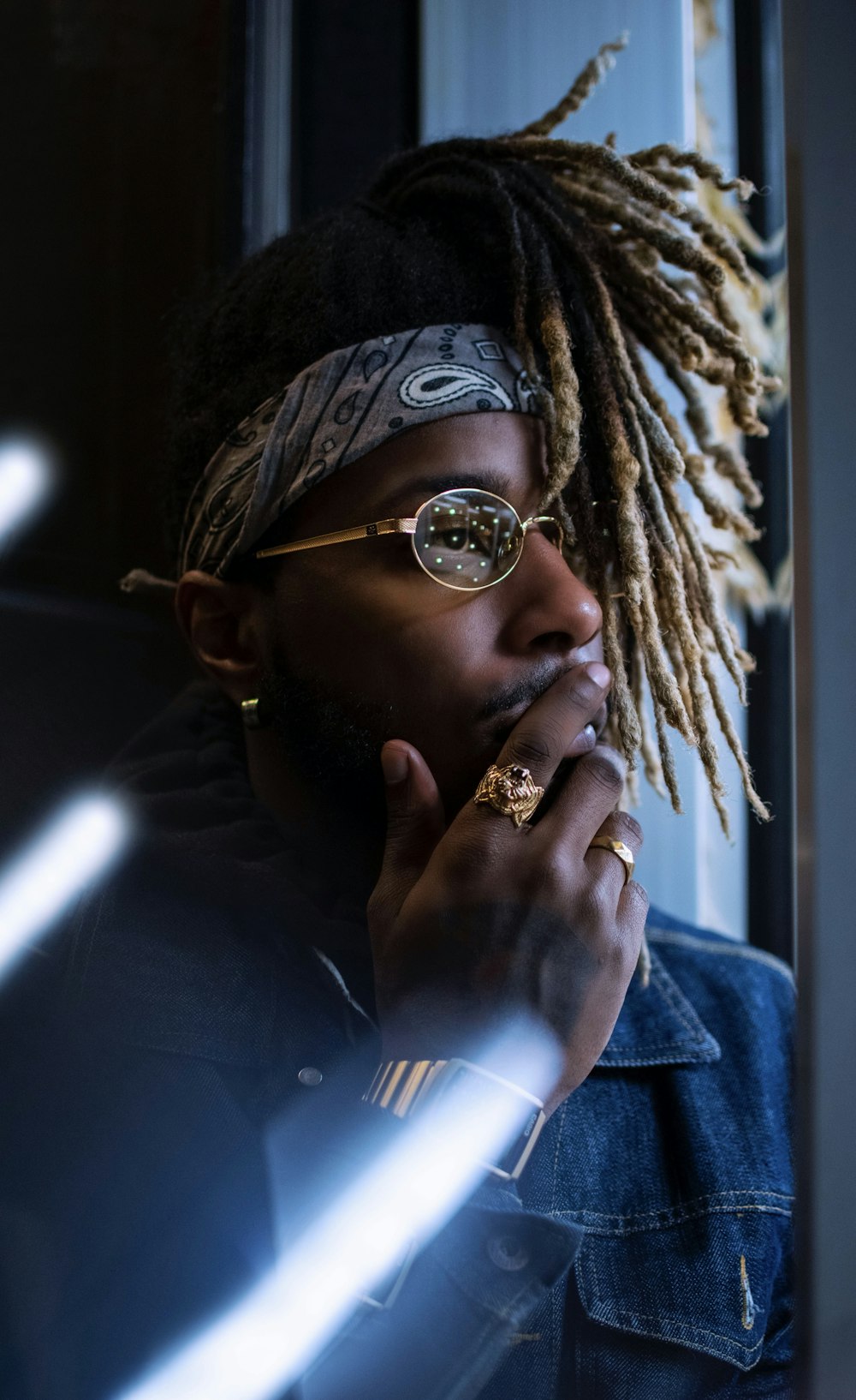 selective focus photo of man right hand on mouth standing in front of window