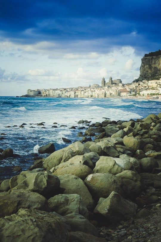 seashore with rocks under blue sky in Cefalù Italy