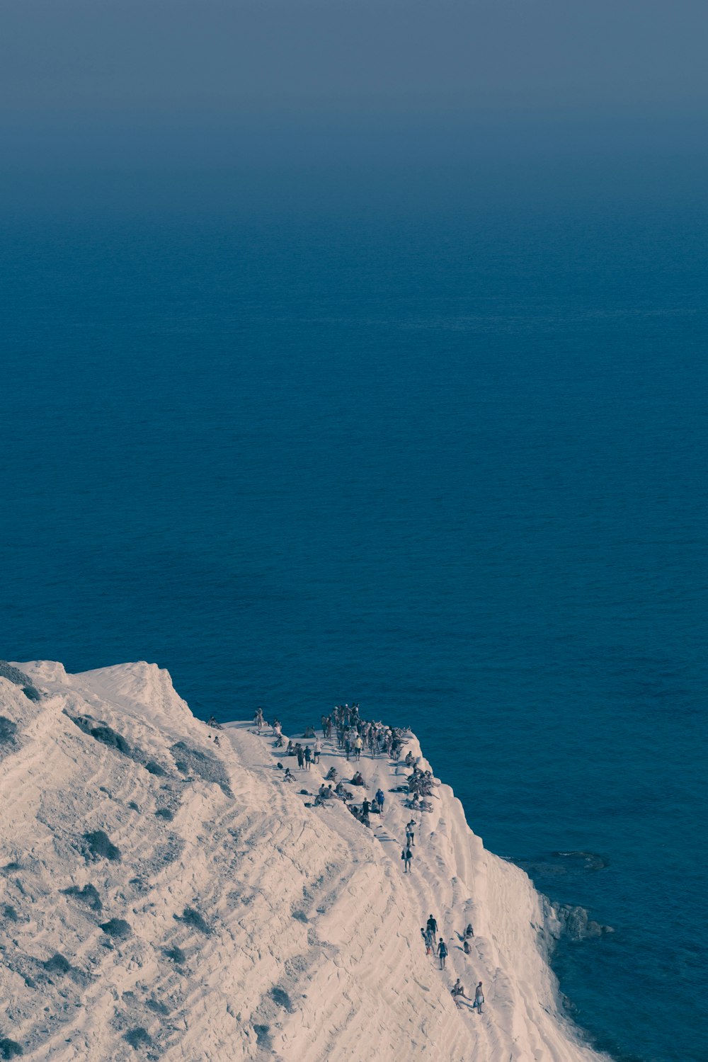 gray rock formation mountain beside large body of water during daytime