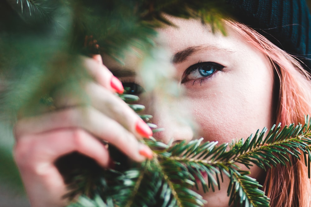 woman hiding behind pine tree leaves