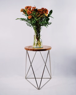 Close-up of a sleek modern vase holding fresh wildflowers, placed on a minimalist white side table.