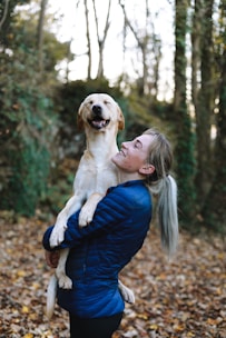 A joyful volunteer gently holding a rescued dog in a sunny shelter garden.