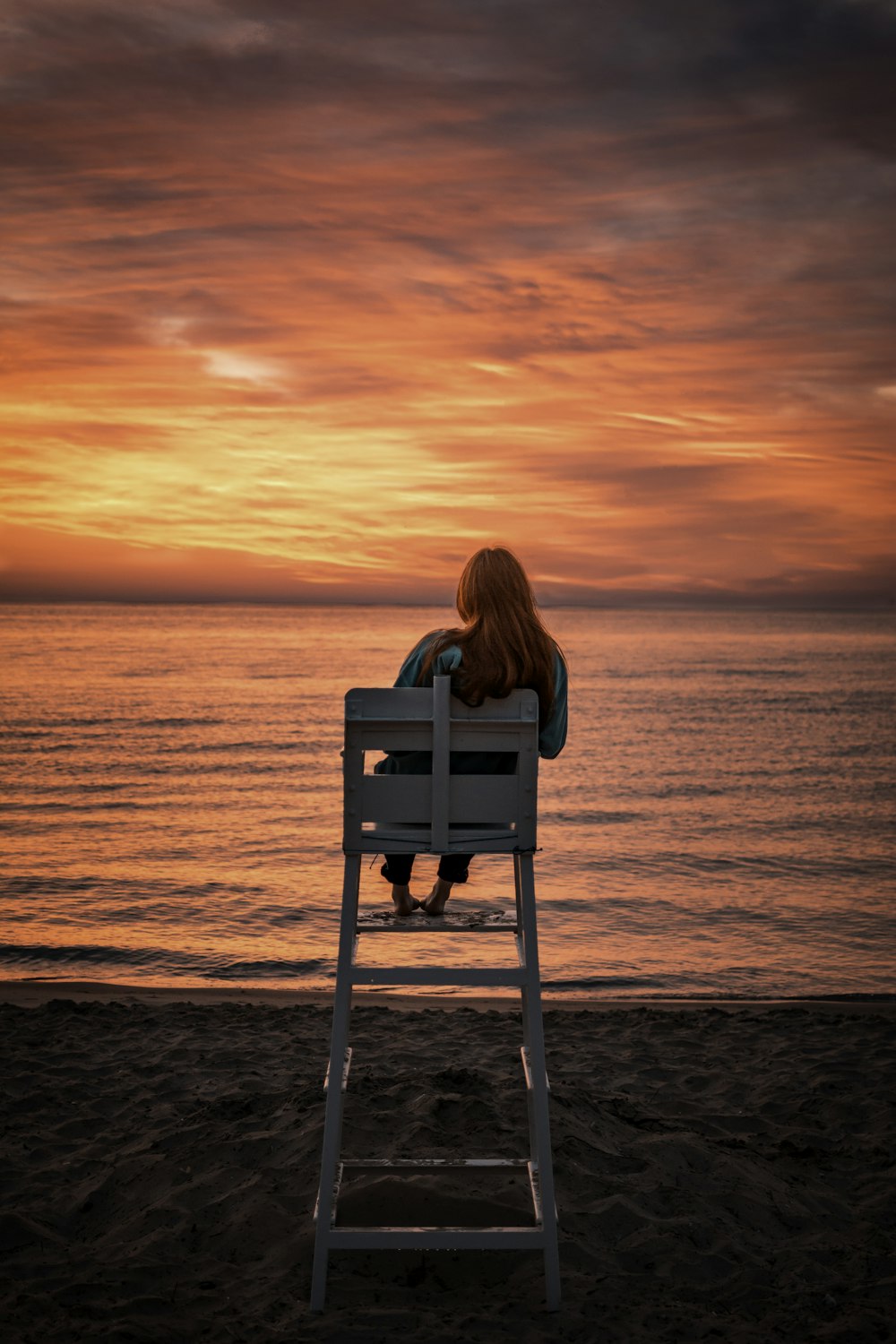 해변을 향한 유아용 의자에 앉아 있는 여자
