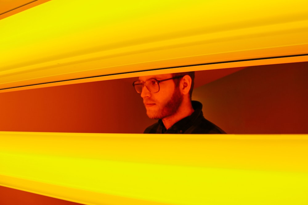 man in black shirt looking through yellow blinds