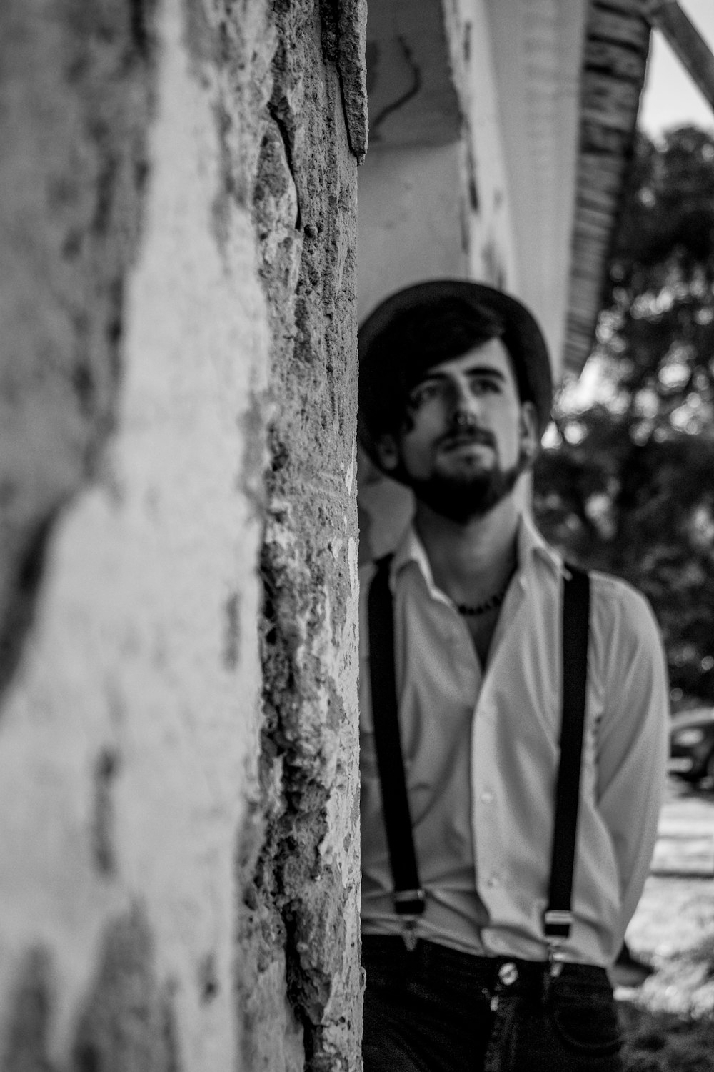 man wearing dress shirt leaning on wall