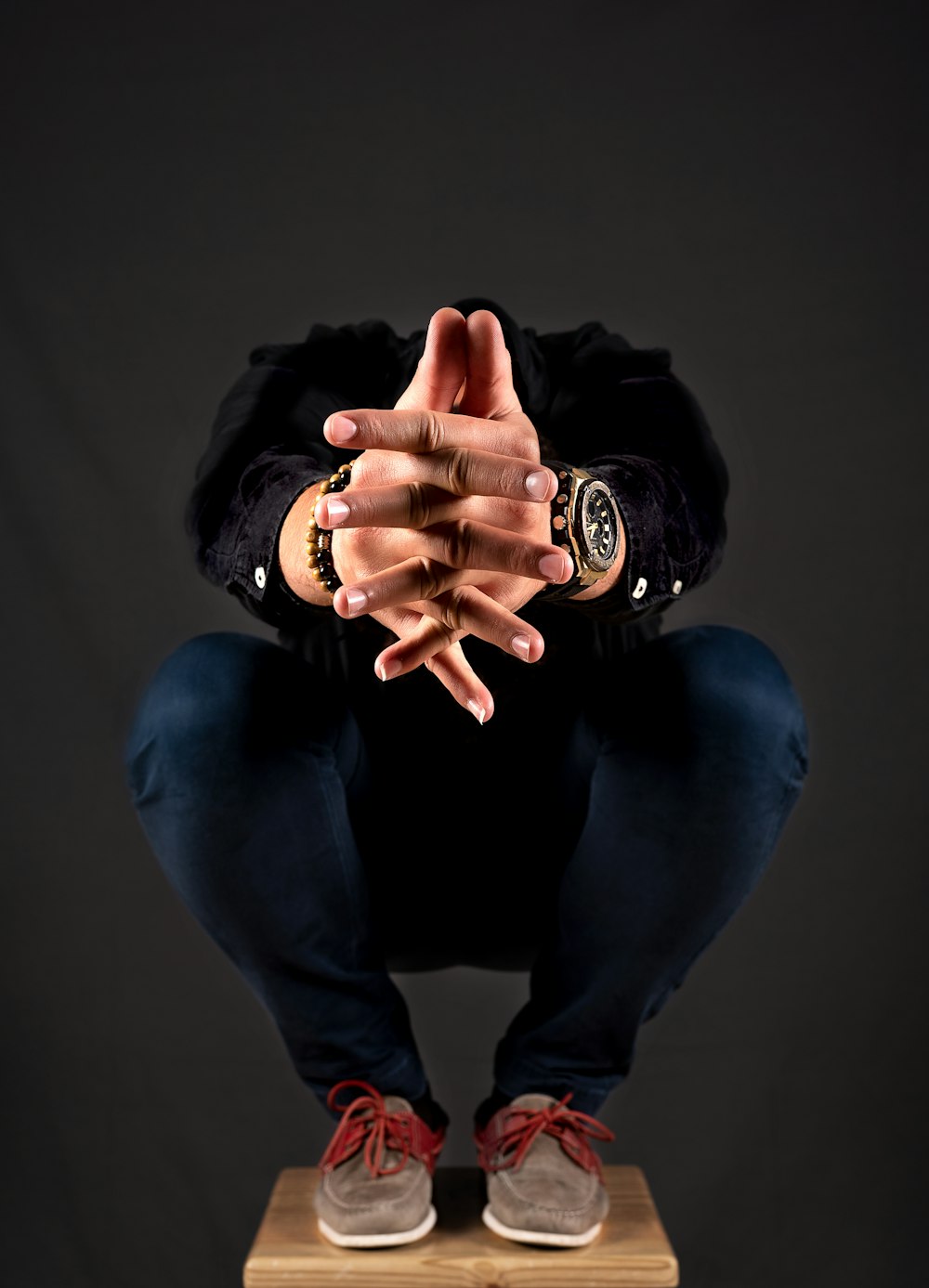 man squatting on brown stool