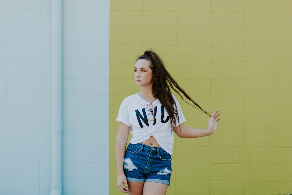 woman standing behind yellow concrete wall during daytime