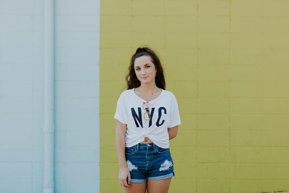 woman standing behind yellow concrete wall during daytime