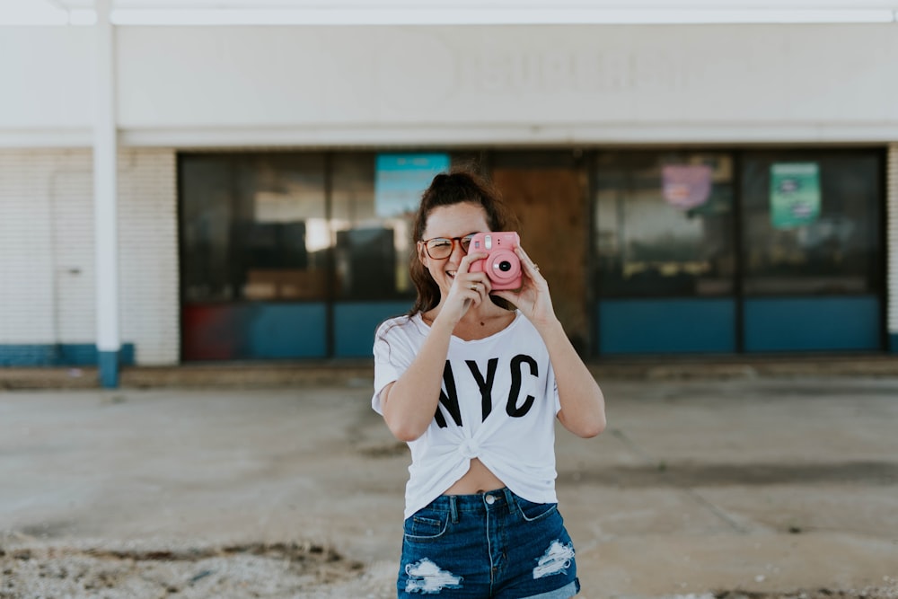 smiling woman holding pink camera