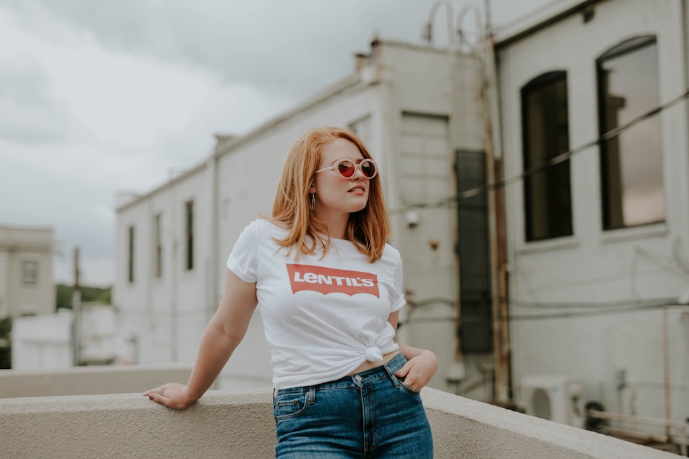 woman leaning on gray concrete wall at daytime