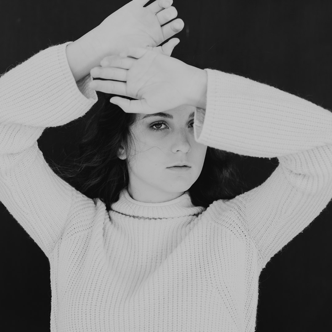 grayscale photography of a woman covering her face with arms