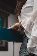 woman wearing white top and wearing gold-colored bracelets
