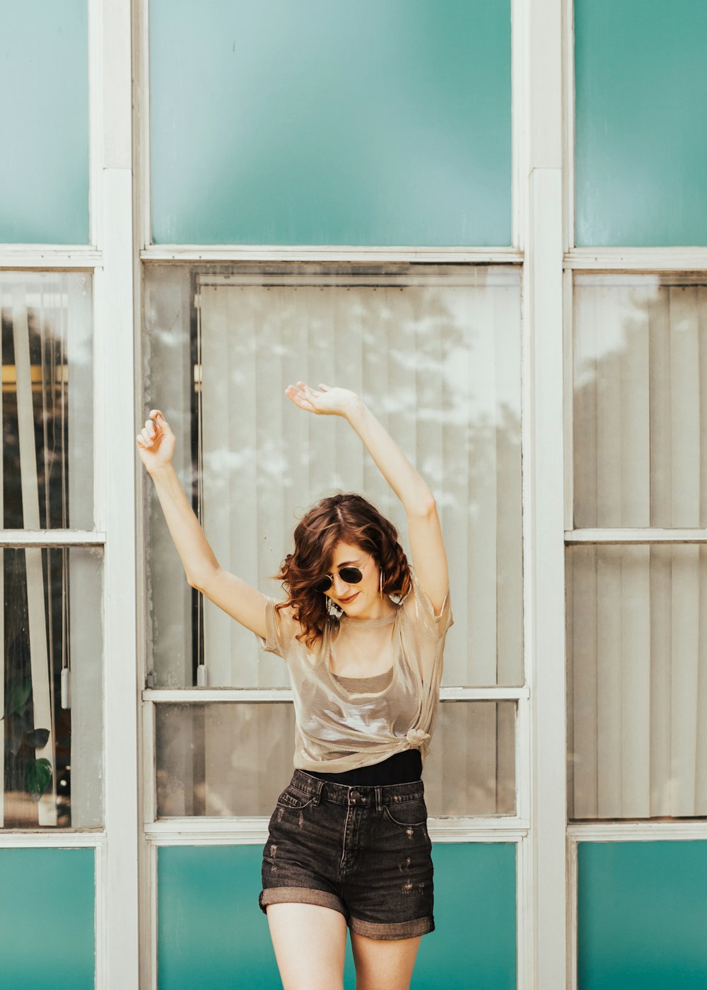 a woman standing in front of a window with her arms in the air