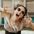 selective focus photography of jolly woman using peace hand gesture