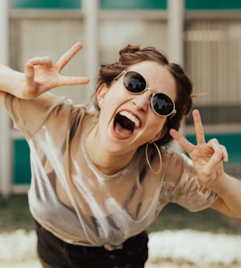 selective focus photography of jolly woman using peace hand gesture