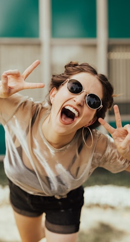 selective focus photography of jolly woman using peace hand gesture