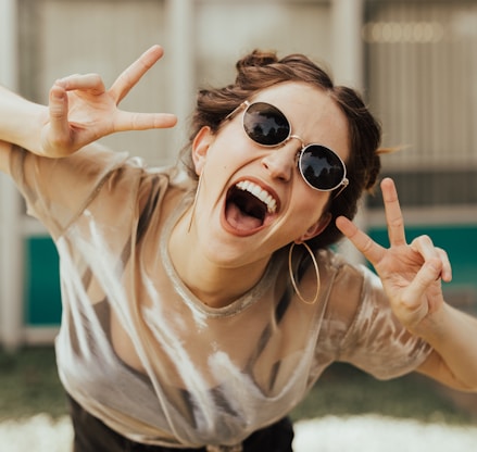 selective focus photography of jolly woman using peace hand gesture