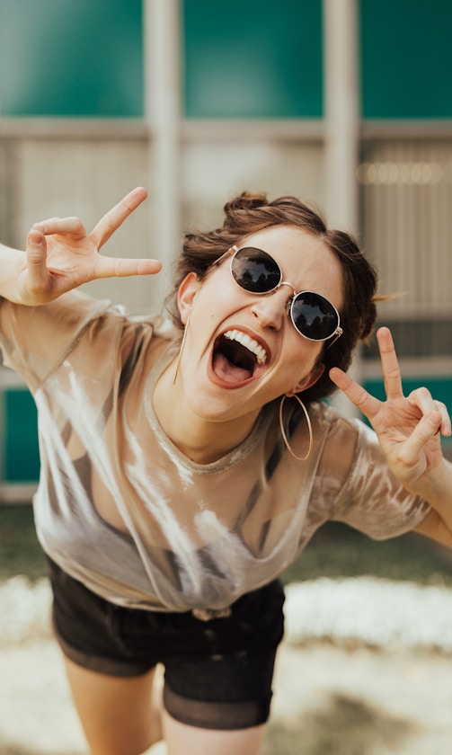 selective focus photography of jolly woman using peace hand gesture