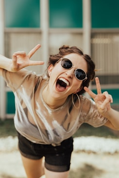 fille sourire lunettes de soleil signe doigts onlyfans mym