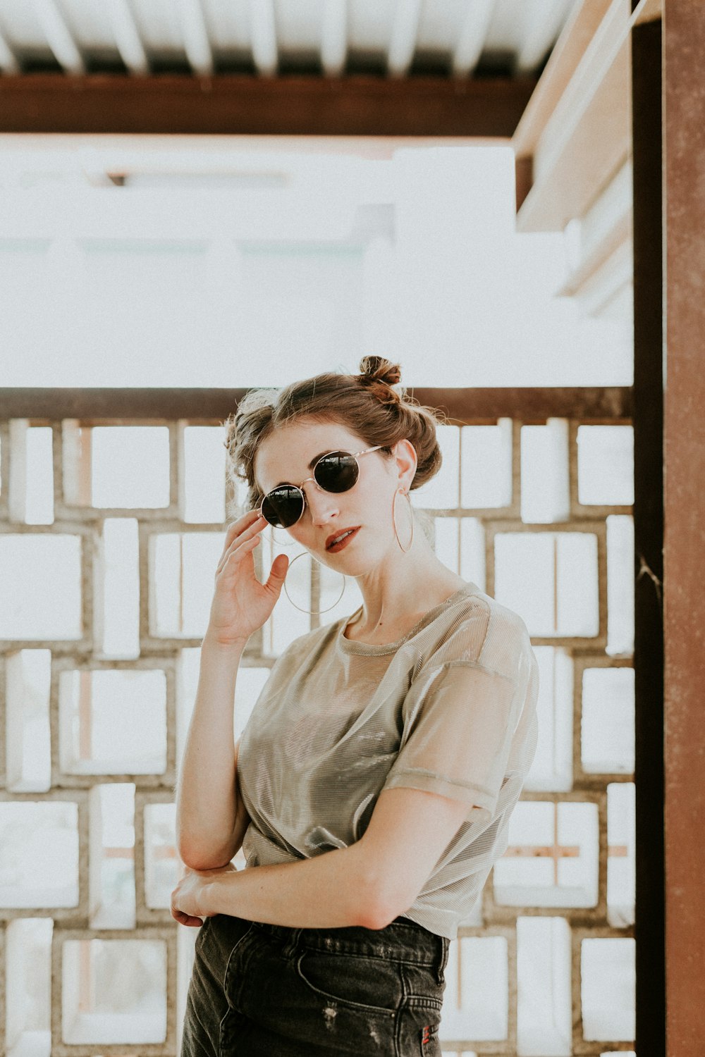 woman standing near wall wearing sunglasses