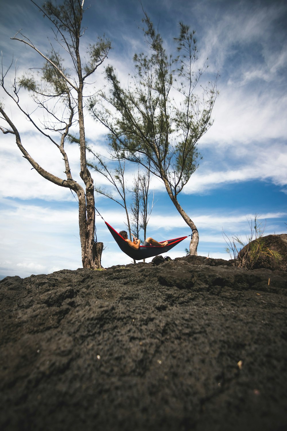 person lying on hammock on hill