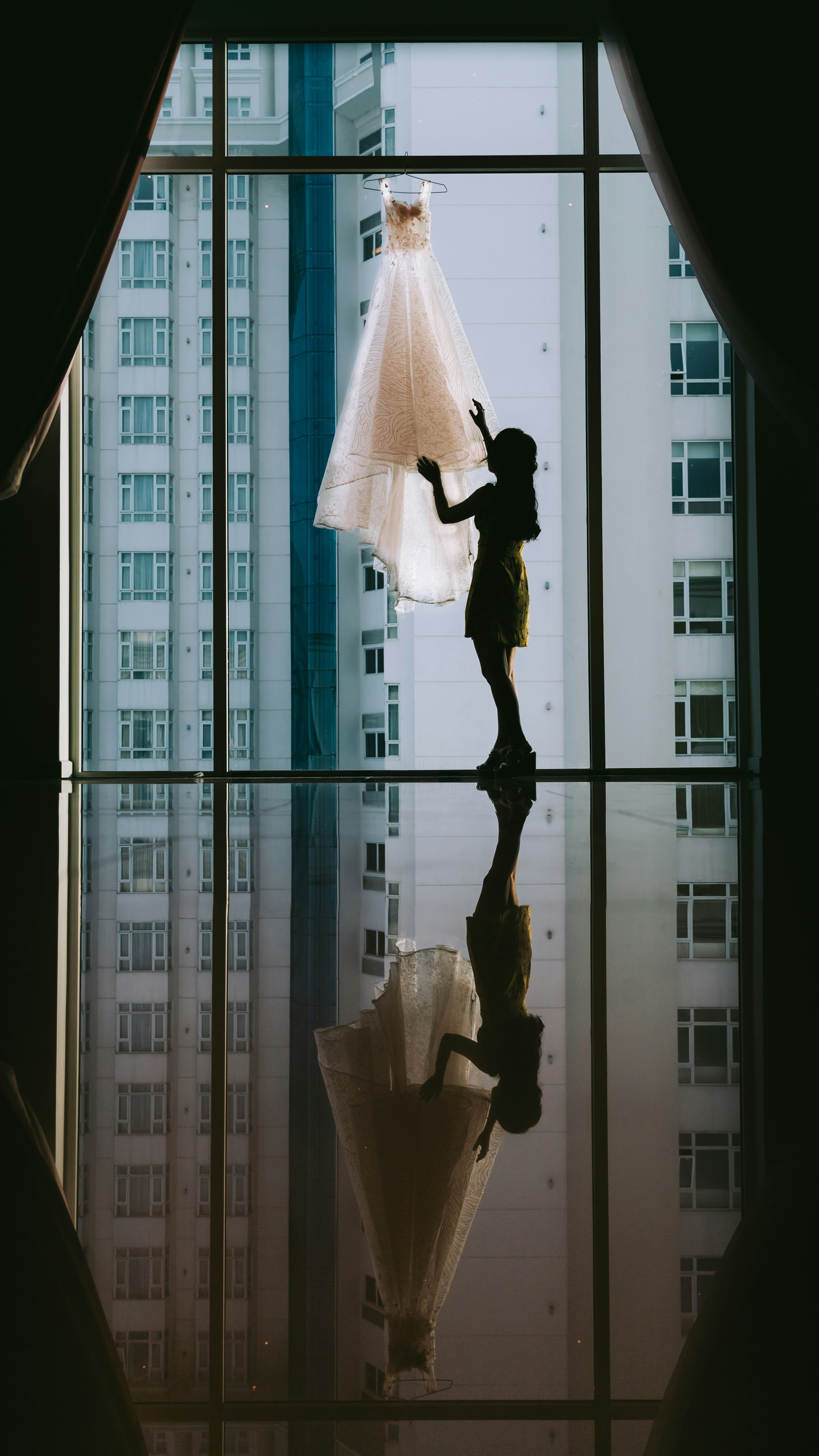 women's white gown hanged on clear glass window