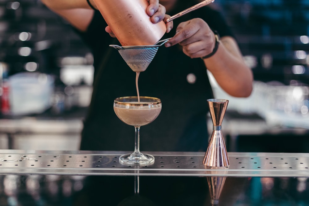 person pouring liquid on glass