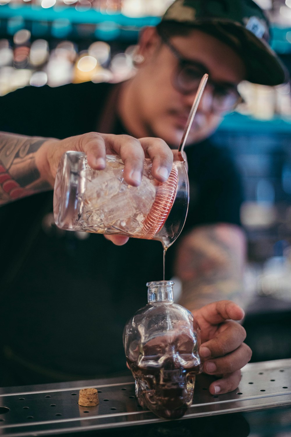 man pouring liquid on glass bottle