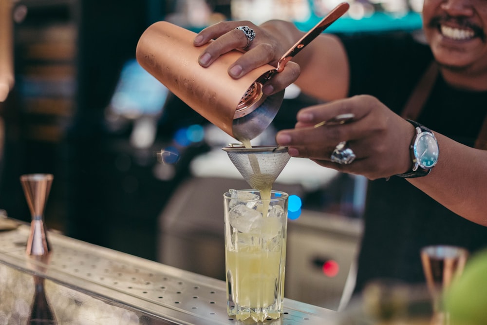 person pouring juice on drinking glass