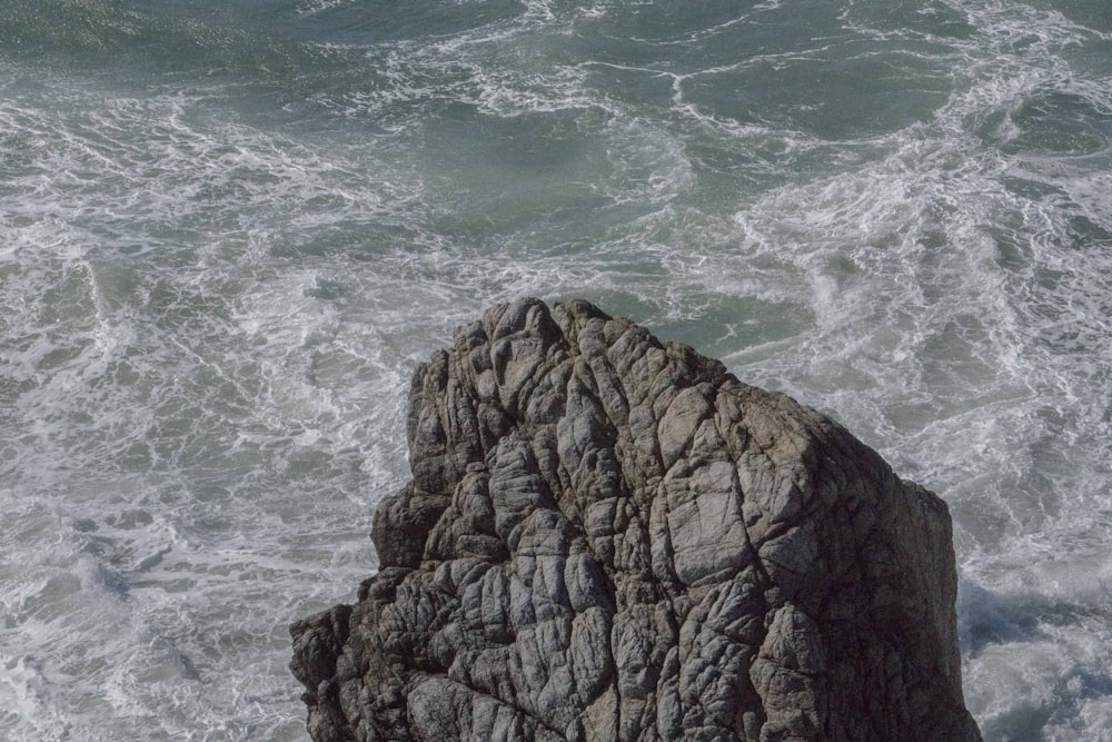 ein großer Felsen, der aus dem Ozean ragt