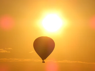 A majestic hot air balloon soaring over Luxor’s temples at sunrise, bathed in warm golden light.