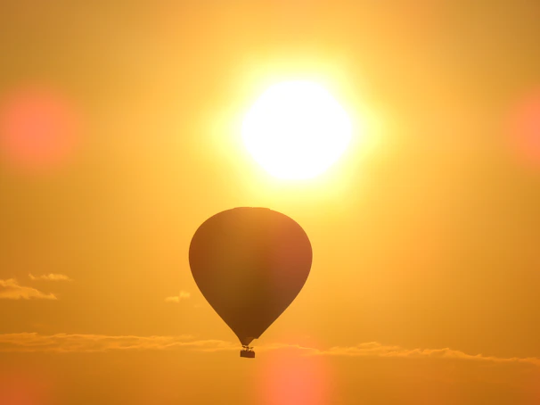 A majestic hot air balloon soaring over Luxor’s temples at sunrise, bathed in warm golden light.