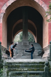 A vintage sepia-toned photograph of Muay Boran fighters training in traditional attire under an ancient temple backdrop.