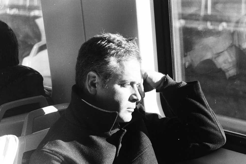 Photographie en niveaux de gris d’un homme assis à l’intérieur du véhicule