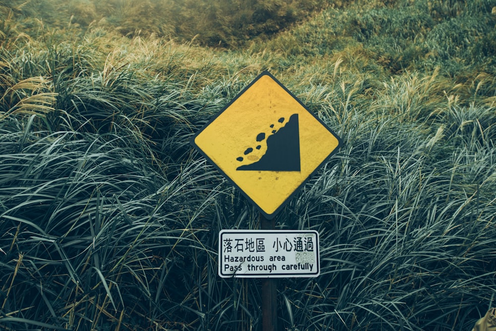 black and yellow metal signage beside green grasses during daytime