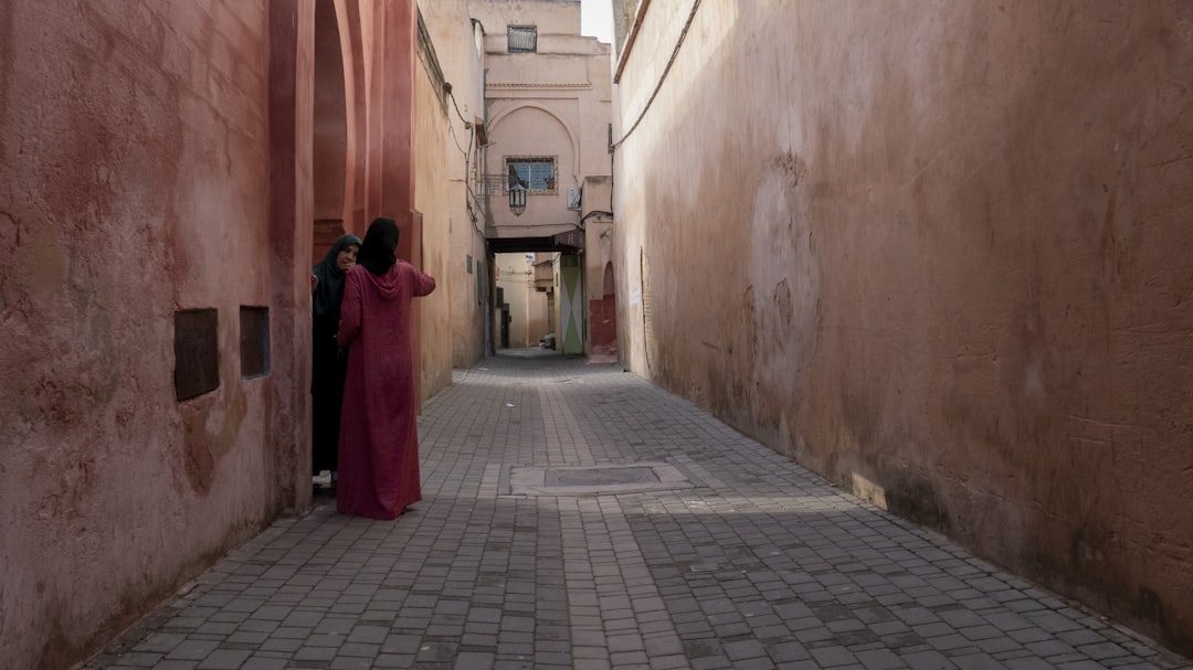 woman standing beside building, Two moroccan women chatting on the threshold of a door on a rose street in Morocco