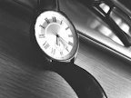 A high-contrast image of a luxury watch and sleek sunglasses arranged on a white marble background.
