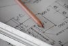 Close-up of a detailed technical architectural blueprint on a desk with a pencil.