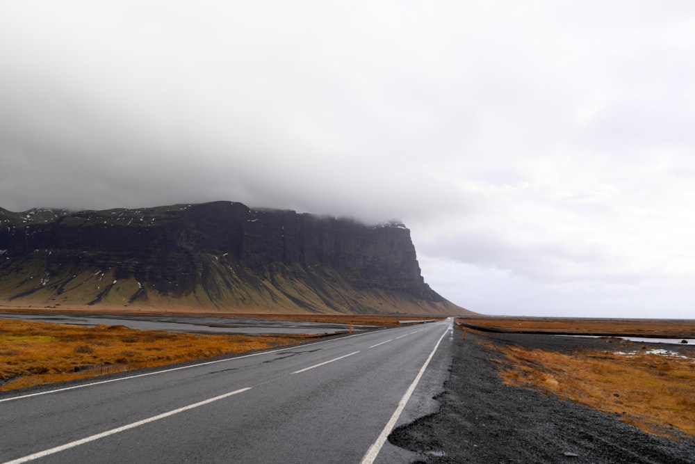 road on plains near mountain under cloudy sky