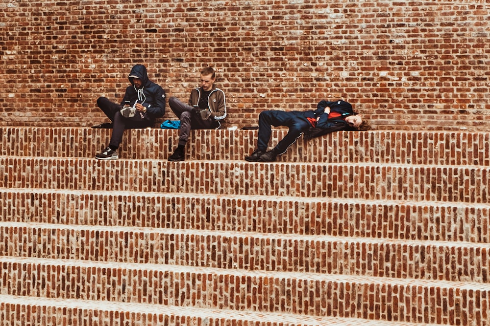 três homens sentados na escada