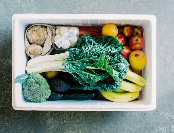 A delivery box branded with Farmfresh Cress logo, filled with fresh salad ingredients, on a doorstep.