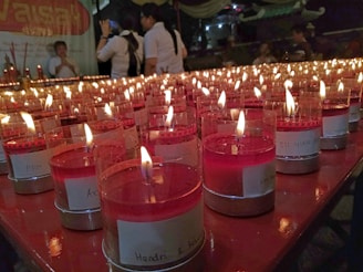 Close-up of hands gently arranging name charts on a wooden table surrounded by candles.