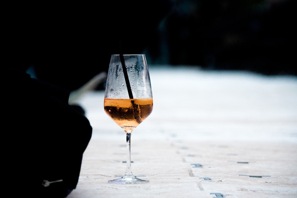 Fotografia a fuoco selettiva del bicchiere di vino mezzo vuoto sul pavimento