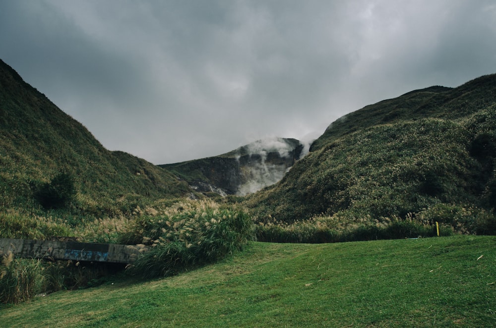 mountains covered with grass under white cloudy sky