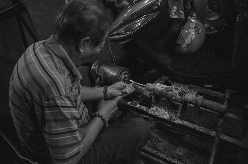 grayscale photograpy of man fixing equipment
