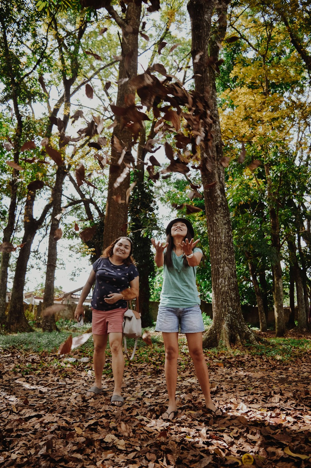 two woman standing near trees