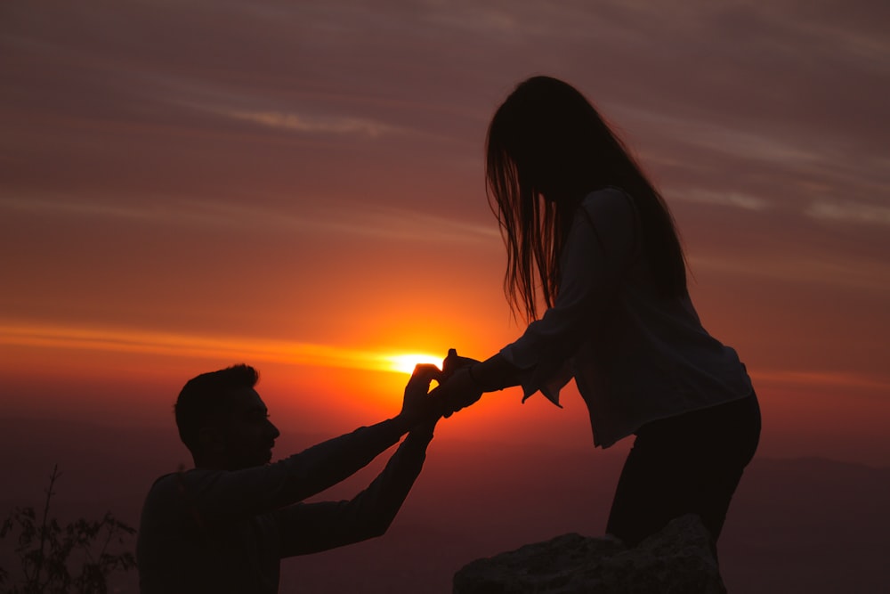 silhouette photography of man kneeling in front of woman