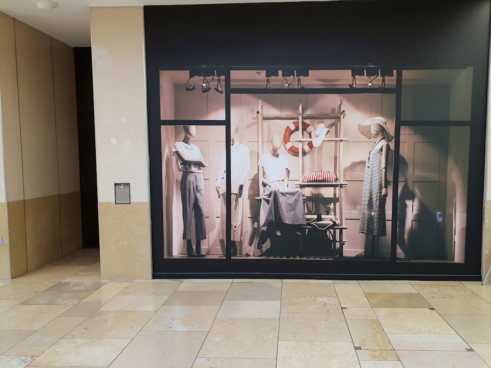 mannequins with clothes displayed inside glass room inside building